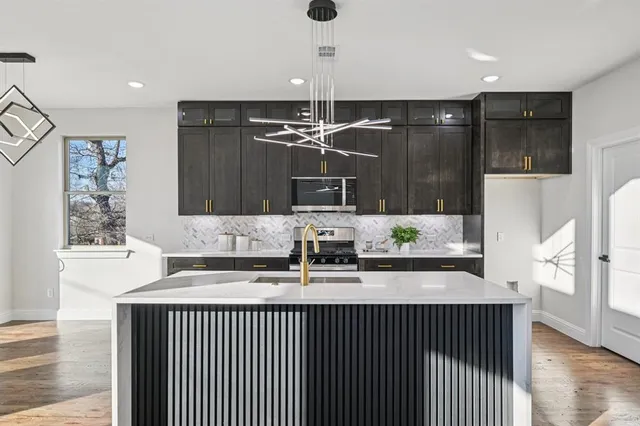 a kitchen with stainless steel appliances kitchen island granite countertop a refrigerator and a sink
