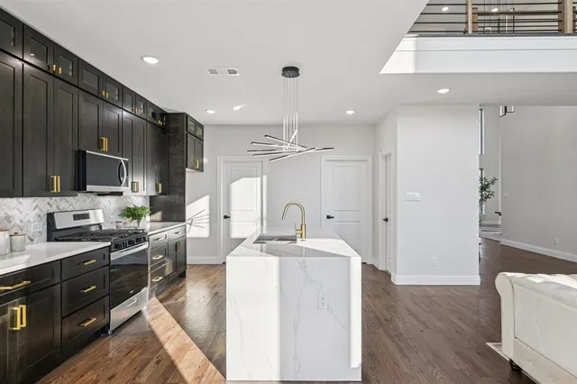 a large kitchen with granite countertop a sink stainless steel appliances and cabinets