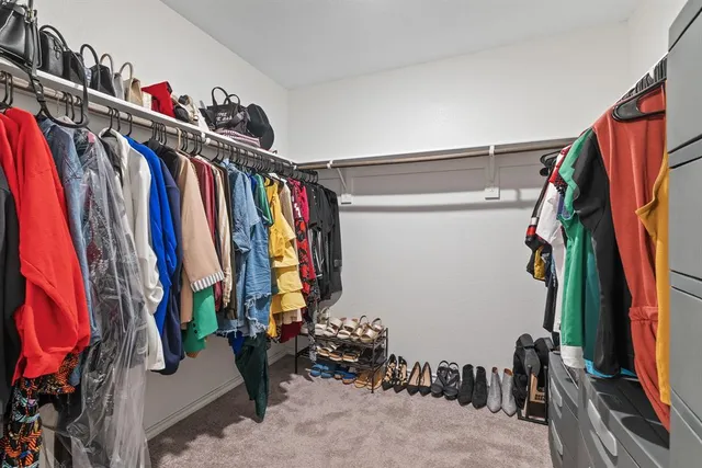 a view of walk in closet with clothes and shoes