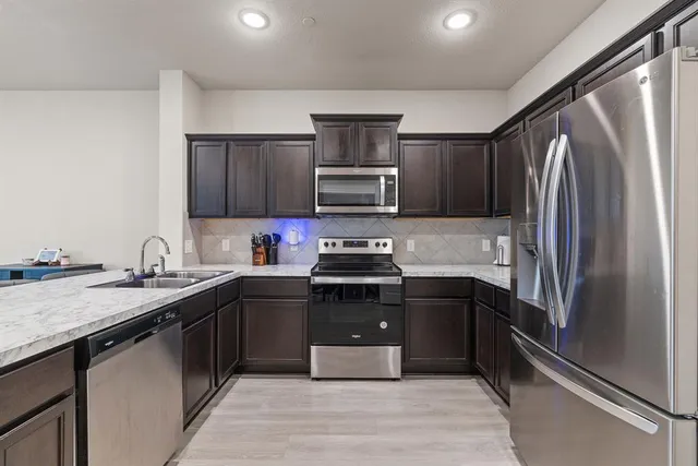 a kitchen with stainless steel appliances granite countertop a refrigerator and a sink