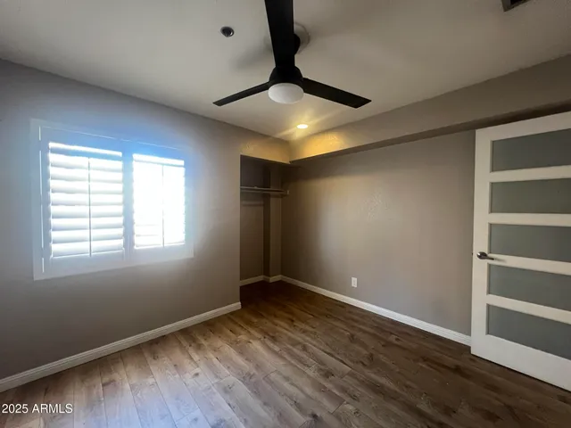 a view of empty room with wooden floor and fan