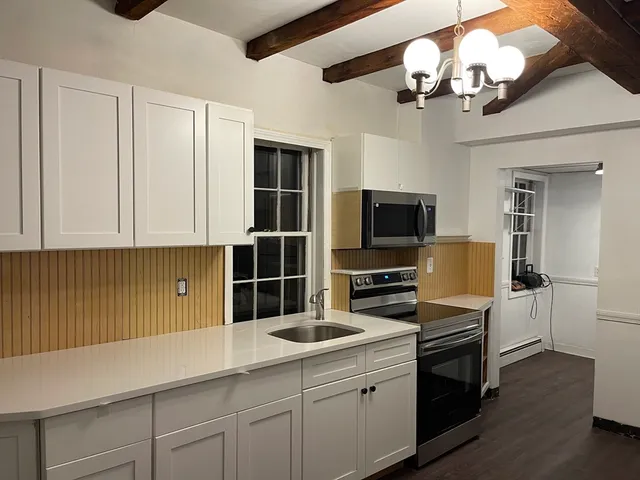 a kitchen with a sink stainless steel appliances and chandelier