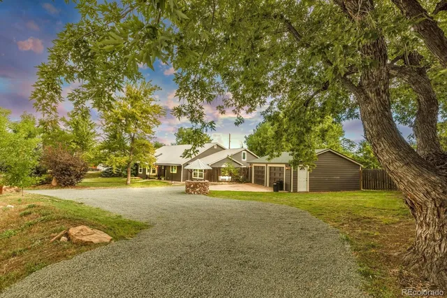 a view of a house with a yard and large trees