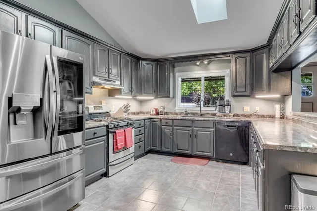 a kitchen with stainless steel appliances granite countertop a refrigerator sink and stove