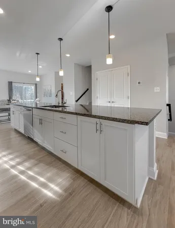 a large kitchen with granite countertop a sink a counter space appliances and cabinets