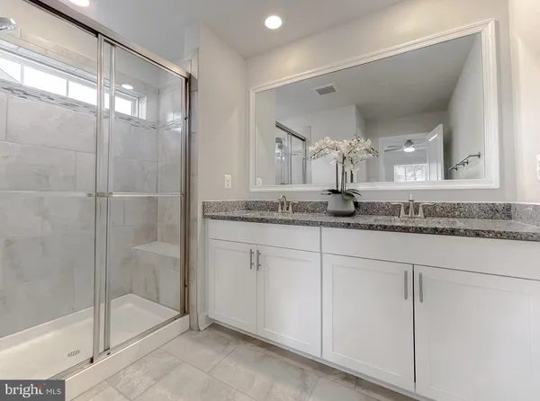 a bathroom with a granite countertop sink a mirror and a shower