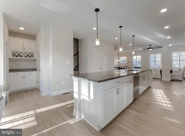 a large kitchen with kitchen island a stove a sink a refrigerator and white cabinets with wooden floor