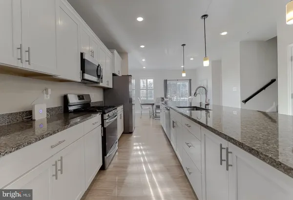 a large white kitchen with stainless steel appliances granite countertop lots of white cabinets a stove and a sink