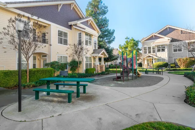 a view of a white house next to a yard with big trees