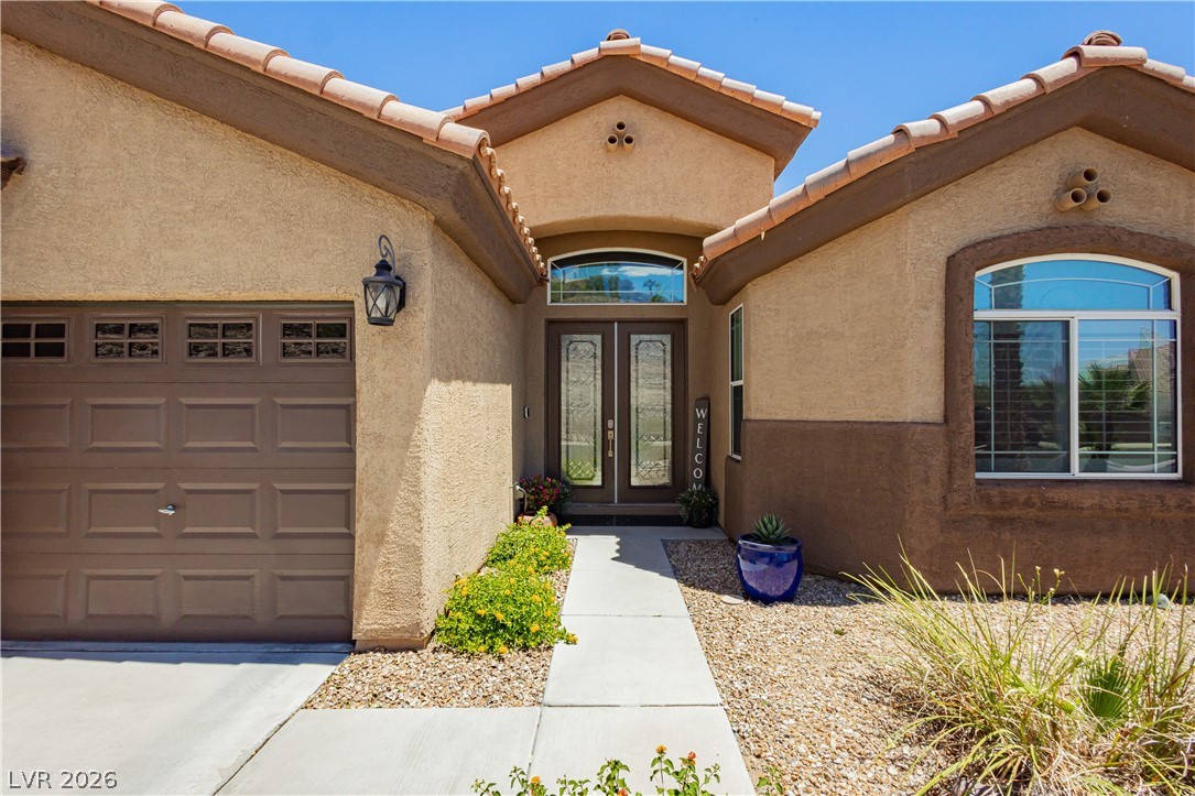 2256 Dogwood Ranch Avenue Henderson, NV 89052 - Photo 2 of 51 A terracotta-tiled roof crowns a welcoming entryway featuring double glass doors and an attached garage.