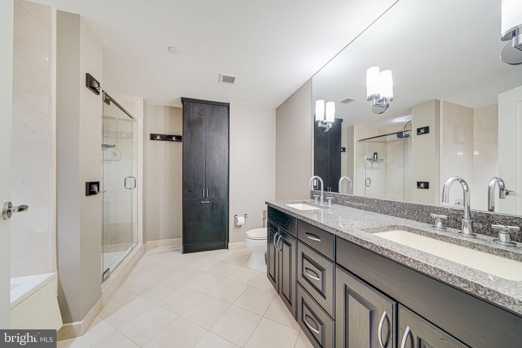 1111 19th Street North, Unit 2703 Arlington, VA 22209 - Photo 36 of 52 a spacious bathroom with a granite countertop sink a mirror and a shower