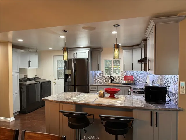 a kitchen with stainless steel appliances kitchen island granite countertop a stove refrigerator and cabinets