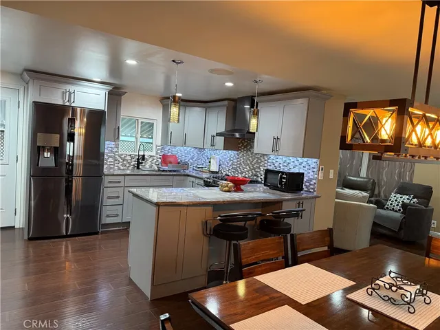a kitchen with stainless steel appliances granite countertop a sink dishwasher stove and refrigerator with wooden floor