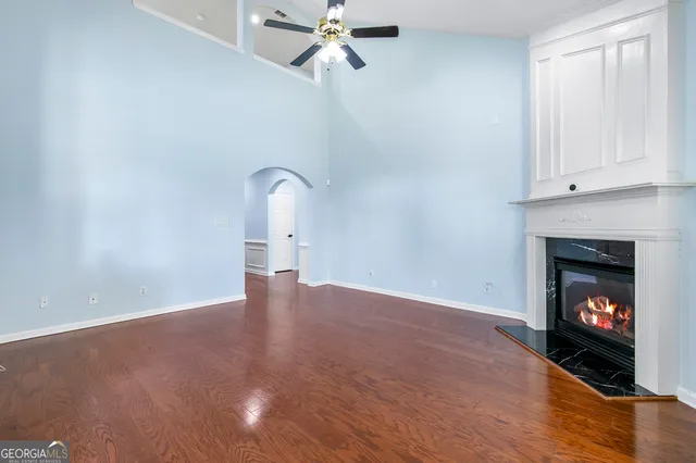 a view of an empty room with wooden floor fireplace and a window
