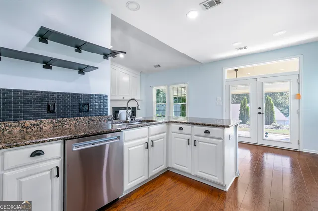 a kitchen with granite countertop a sink cabinets and wooden floor