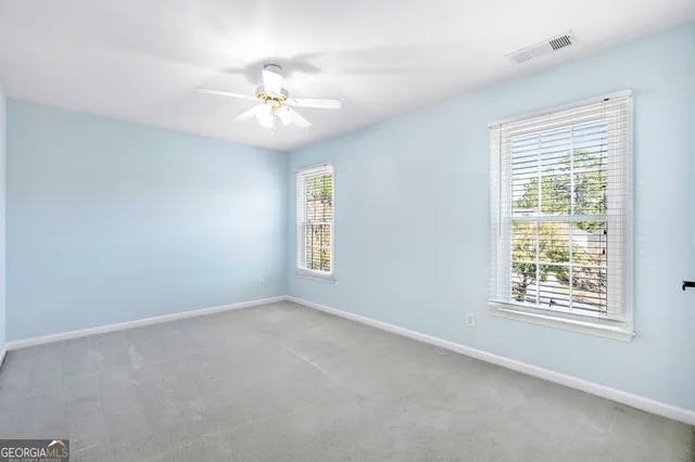 an empty room with windows and fan