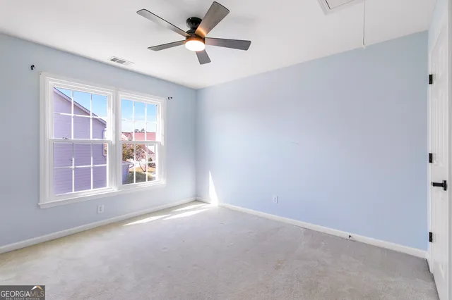 an empty room with windows and fan