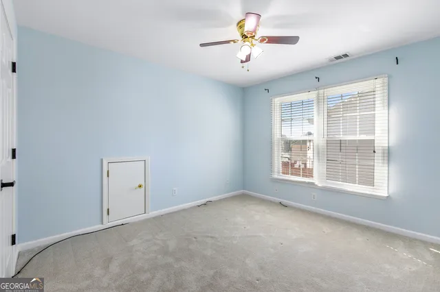 an empty room with windows and chandelier fan