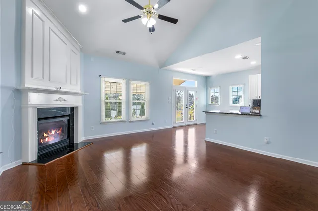 a view of an empty room with wooden floor fireplace and a window