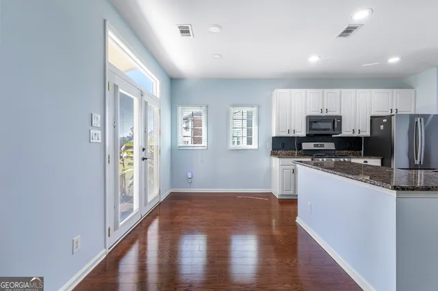 a kitchen with granite countertop a refrigerator and a stove top oven
