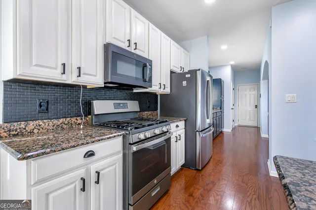 a kitchen with stainless steel appliances granite countertop a stove a refrigerator and a microwave
