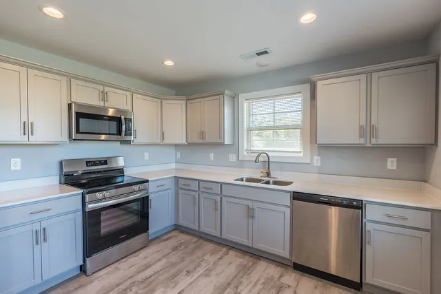 a kitchen with sink a microwave a stove and cabinets