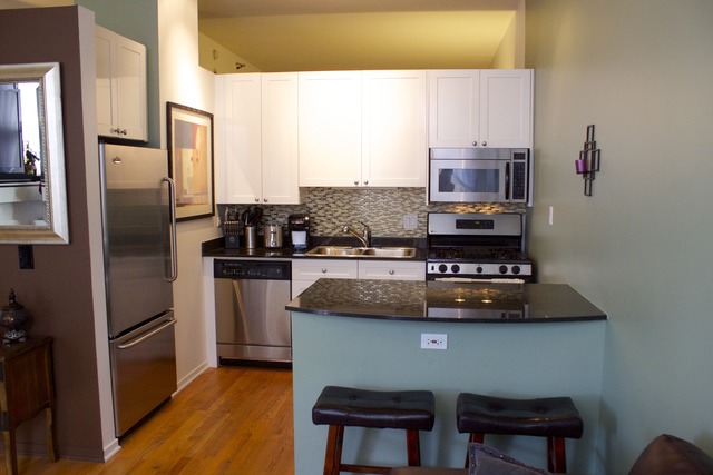 1201 West Adams Street, Unit 709 Chicago, IL 60607 - Photo 5 of 16 a kitchen with stainless steel appliances granite countertop a refrigerator and a stove top oven