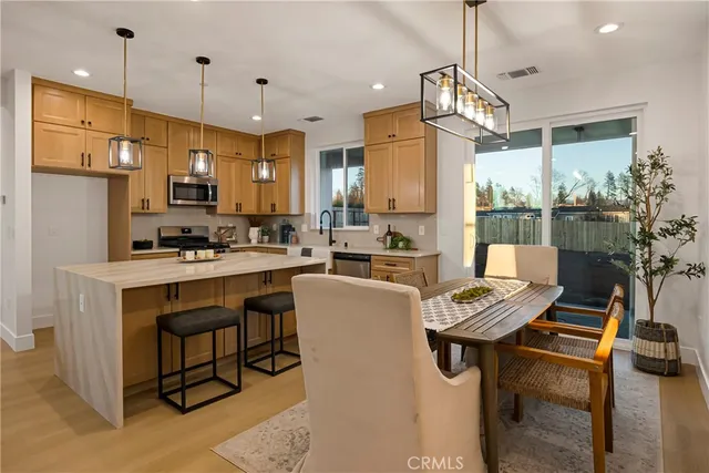 a kitchen with kitchen island granite countertop a table chairs stove a sink and a refrigerator