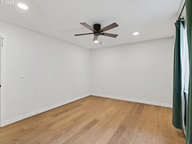 a view of a room with wooden floor and a ceiling fan