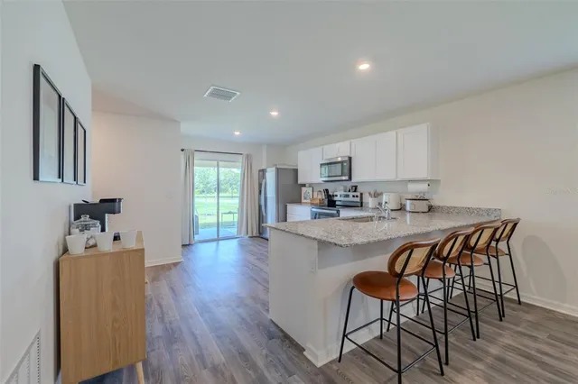 a kitchen with stainless steel appliances granite countertop a table chairs sink and cabinets