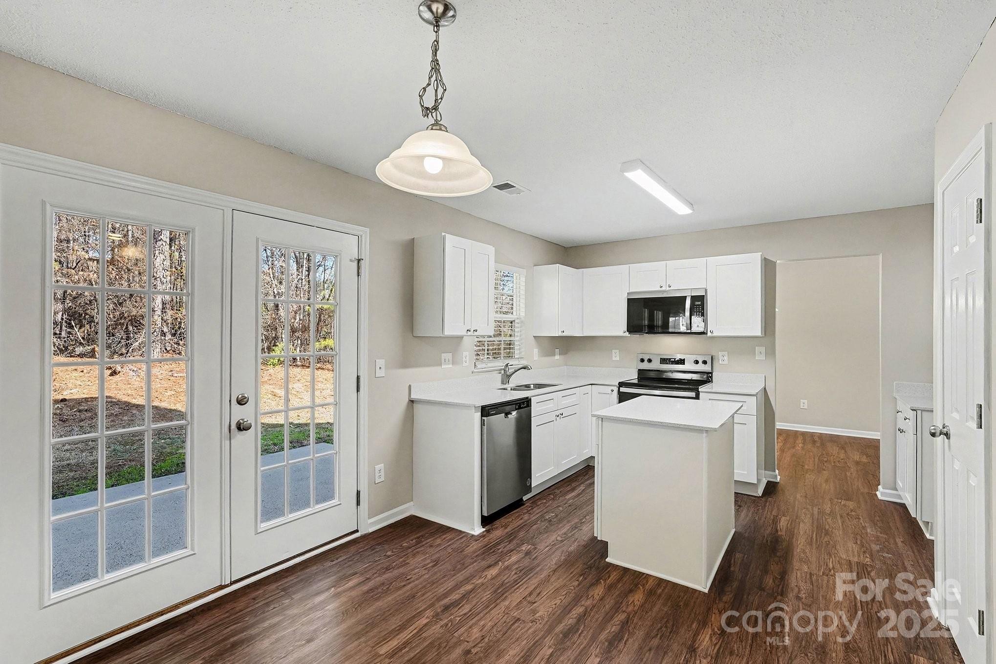 1655 Summit Ridge Lane Kannapolis, NC 28083 - Photo 7 of 17 a kitchen with stainless steel appliances a stove a sink dishwasher a refrigerator and white cabinets with wooden floor