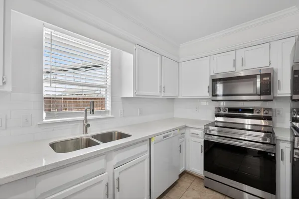 a kitchen with white cabinets appliances and a sink