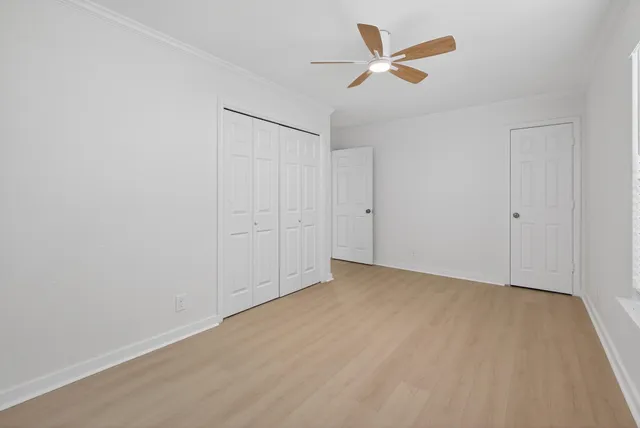an empty room with ceiling fan and window