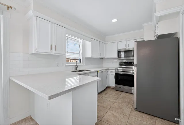 a kitchen with a refrigerator stove top oven and white cabinets