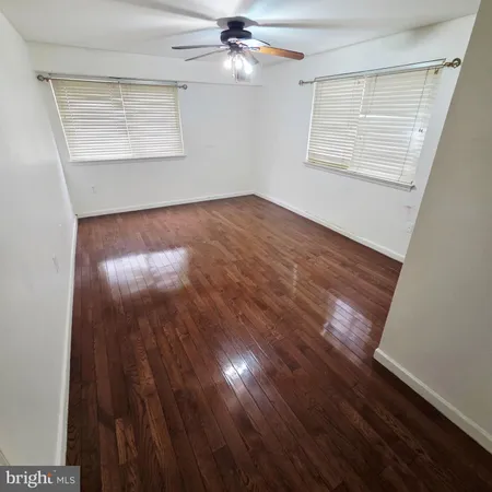 an empty room with wooden floor cabinet and windows