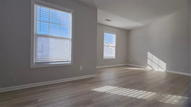 an empty room with wooden floor and windows