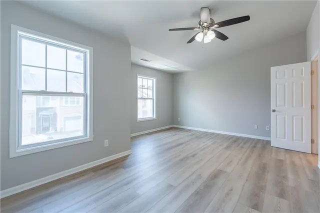 a view of empty room with wooden floor and fan