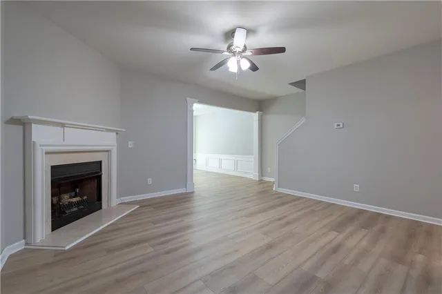a view of an empty room with wooden floor and fireplace