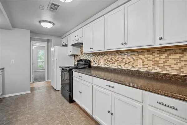 a kitchen with granite countertop white cabinets and stainless steel appliances