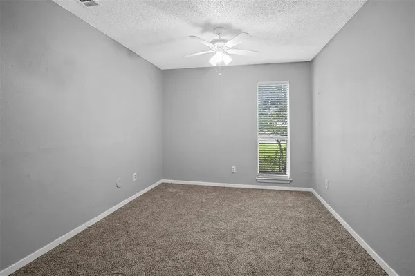 an empty room with windows and ceiling fan