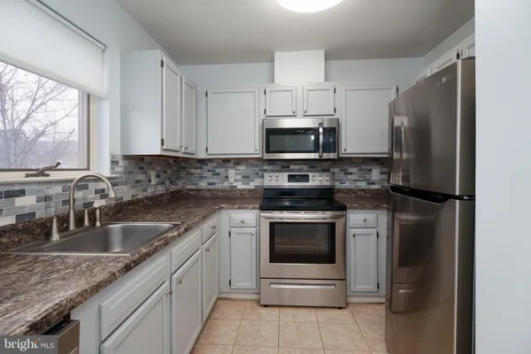 a kitchen with stainless steel appliances granite countertop a sink stove microwave and refrigerator