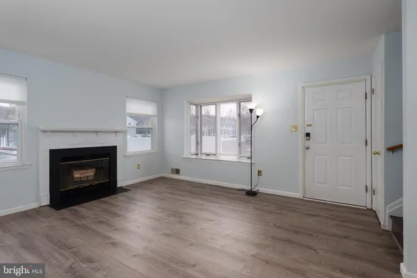 an empty room with windows a fireplace and wooden floor