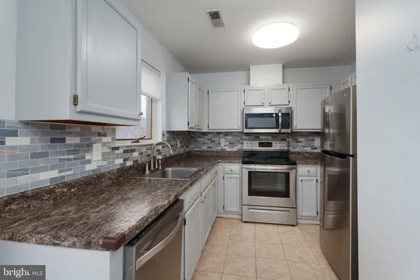 a kitchen with granite countertop a sink stove and microwave