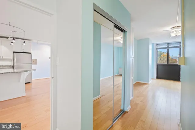 a view of a hallway with wooden floor and a bathroom