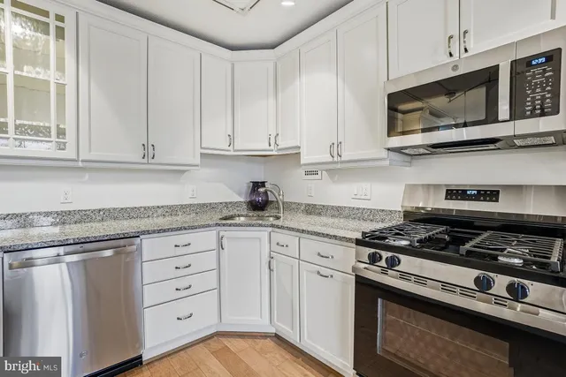 a kitchen with granite countertop white cabinets and stainless steel appliances