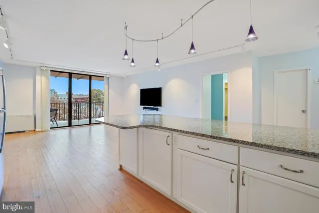 a living room with hard wood floors and white stainless steel appliances