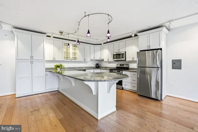 a kitchen with stainless steel appliances granite countertop a refrigerator a stove a sink dishwasher and a microwave with wooden floor