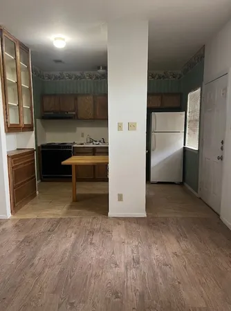 a view of a hallway to room and kitchen