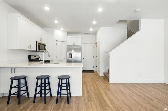 1221 West 1870 South Logan, UT 84321 - Photo 4 of 20 Open-concept kitchen featuring white cabinetry, stainless steel appliances, a breakfast bar, and recessed lighting