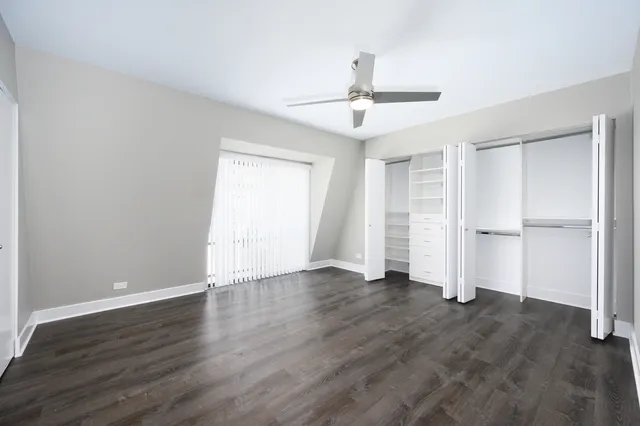 an empty room with wooden floor closet and windows